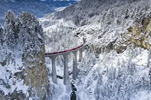 Red Train Prints: Bernina Express train on Landwasser viaduct in a snowy winter, Filisur