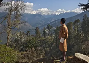 A Bhutanese man in national costume views an eastern Himalayan mountain range from the 11