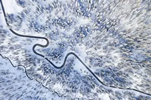 Larix Prints: the black snake that leads to Giau Pass, surrounded by trees and snow-covered meadows