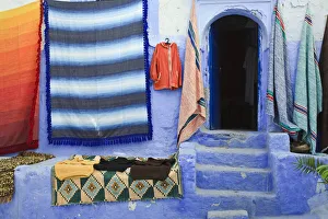 Hanging Prints: Blue doorway and traditional Moroccan fabrics, Chefchaouen, Morocco