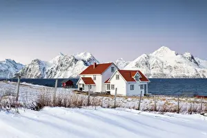 Cold Prints: Blue sky on the wooden huts called Rorbu framed by frozen sea and snowy peaks Djupvik