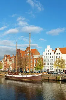 Lubeck Prints: Boat anchored on Trave river and houses with traditional gables in background