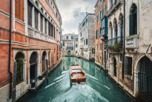 A boat cruising a green canal in Venice, Veneto, Italy