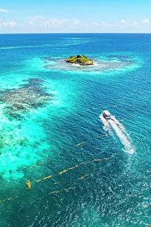 Leeward Islands Prints: Boat for tourists sailing in the clear blue sea approaching the reef