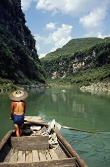 Images Dated 5th February 2009: A boatman rows between the hills and cliffs of the Chong an River