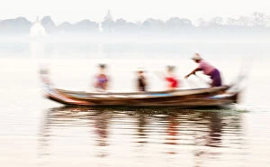 Tourists Gallery: A boatman taking tourists in his traditional wooden boat across the Taungthaman Lake