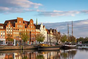 Boats anchored on Trave river and houses with traditional gables in background at sunset, Lubeck, UNESCO, Schleswig-Holstein, Germany