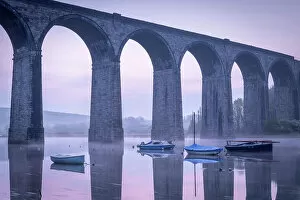 Boats beneath St Germans Victorian viaduct at dawn, St Germans in Cornwall, England. Spring (April) 2022