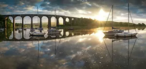 Boats moored on the River Tiddy at dawn below the Victorian viaduct at St Germans, Cornwall, England. Spring (May) 2022