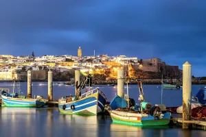 Downtown District Prints: Boats moored along the waterfront with the old medina on background at dusk