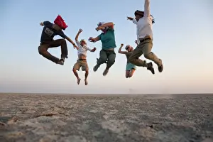 Family Prints: Botswana, Makgadikgadi. A family jump high in the air above the Makgadikgadi salt pans