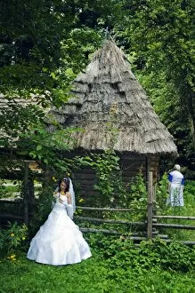 Images Dated 5th August 2006: Bride stood in front of a traditional thatched roof