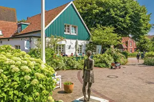 Spiekeroog Prints: Bronze statue island girl and tea room in the village center of Spiekeroog