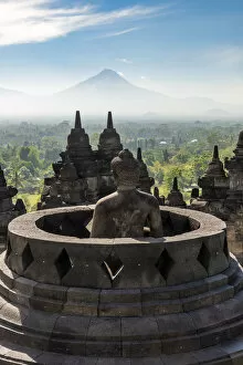 Images Dated 13th September 2018: Buddha statue with Mount Merapi in the background, Candi Borobudur buddhist temple