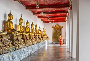 Buddha statues in Wat Pho (Temple of the Reclining Buddha) with a monk in the background