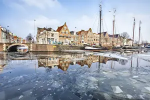 Buildings in Harleem reflecting in the half-frozen Spaarne River, Holland