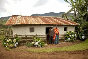 Burundi. A couple outside a traditional house on their farm