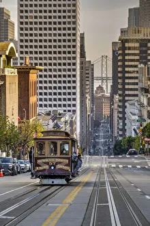 Images Dated 23rd March 2022: Cable car crossing California Street with Bay Bridge backdrop, San Francisco, California, USA