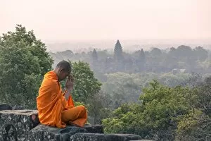 Oriental Flavours Collection: Cambodia, Siem Reap, Angkor Wat complex. Monk meditating with Angor wat temple in the background