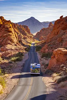 Cars Prints: Campervan and cars driving on a straight road between red rocks during sunny day