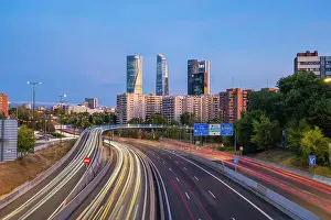 Highways Prints: Car light trails on urban highway with Four Towers Business district in Paseo de la Castellana at twilight