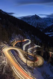 Car lights on the curvy Maloja Pass road at night. Maloja Pass, Engadin, Graubunden
