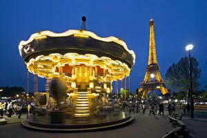 Carousel below the Eiffel Tower at twilight, Paris France