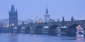 Charles Bridge and Old Town Bridge Tower against snowy sky in winter, Prague, Bohemia