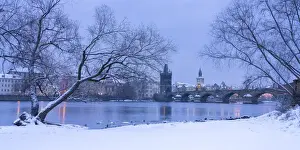 Charles Bridge and Old Town Bridge Tower against snowy sky in winter, Prague, Bohemia