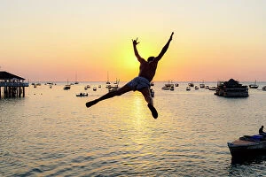 Tanzania Collection: Cheerful young man jumping into the sea at sunset, Stone Town, Zanzibar, Tanzania
