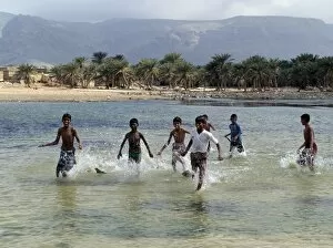 Socotra Island Collection: Children enjoy a boat race in a lagoon at Qalansiah