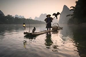 Yangshuo Gallery: China, Guanxi, Yangshuo. Old chinese fisherman at sunrise on the Li river, fishing with cormorants