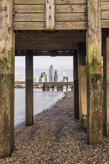 Pebble Prints: City of London skyline through a wooden bridge on the River Thames, London, England