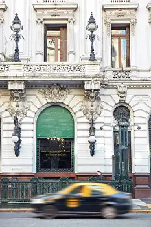 A city taxi passing by the main facade of La Prensa building (Casa de la Cultura), Avenida de Mayo, Monserrat, Buenos Aires, Argentina