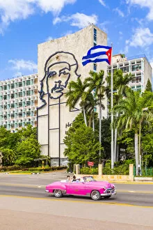 Images Dated 27th May 2020: A classic car driving in front of a building with an outline of Che Guevara