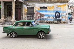 Street Art Prints: A classic car driving in a front of Che Guevara street art in La Habana Vieja (Old Town)