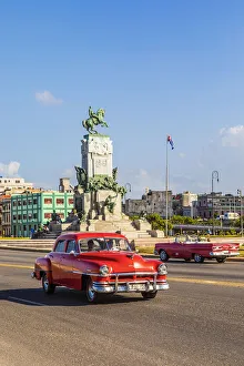 Habana Prints: A classic car driving in front of Parque Antonio Maceo on the Malecon