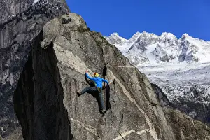 Snowy Peaks Prints: Climber on steep rock face in the background blue sky and snowy peaks of the alps