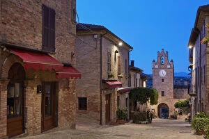 The clock tower of the medieval village of Gradara before sunrise with the hills in