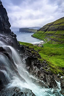 Grass Collection: Cloudy sky over a scenic waterfall in summer, Tjornuvik, Streymoy Island, Faroe Islands