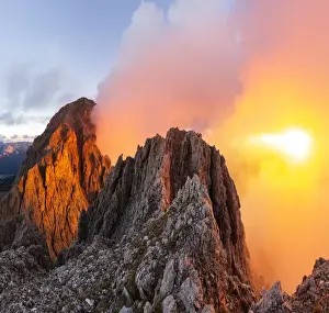 Cloudy sunset with Roda de Vael peak illuminated and backlight red clouds from the rocks