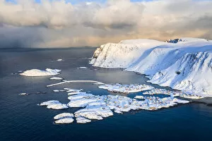 Coastal village of Sorvaer covered with snow during sunrise in the cold arctic winter (Soroya Island, Hasvik)