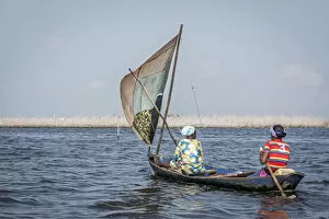 two colorfully dressed local women in wooden sailing canoe on the lake