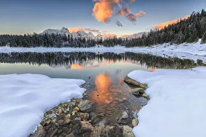 The colors of dawn on the snowy peaks and woods reflected in PalAAAEAAAAA¹ Lake Malenco