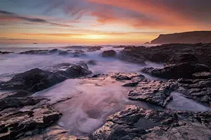 April Prints: Colourful Cornish sunset above rocky ledges near Polzeath
