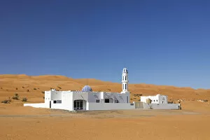 Oman Collection: A colourful mosque stands in front of sand dunes at the edge of the desert, Wahiba sands