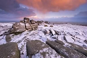Colourful sunrise above snow covered moorland, Belstone Tor, Dartmoor, Devon, England