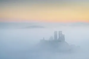 Corfe Castle emerging from mist on a frosty wintry morning, Dorset, England. Winter (February) 2023