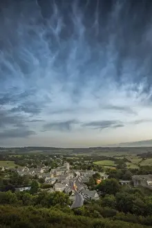 Corfe Castle village with storm clouds above viewed from East Hill, Dorset, England, UK