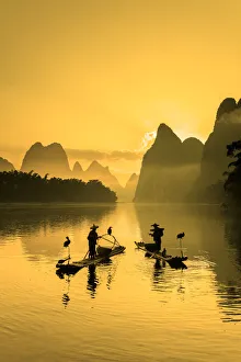 Cormorant fisherman throwing net on Li River at dawn, Xingping, Yangshuo, Guangxi, China